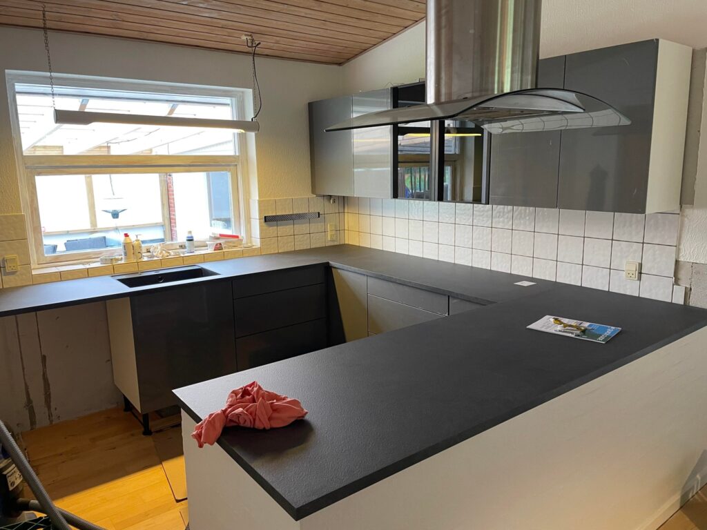 Moderne køkken med grå skabe og sort bordplade