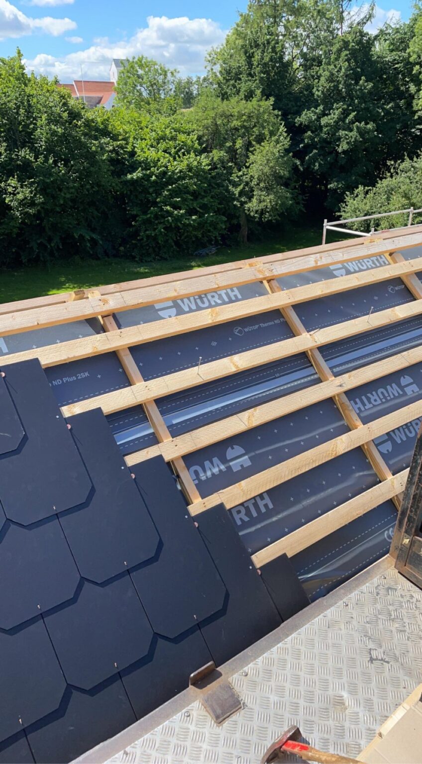 Tagkonstruktion under byggeri med sorte tagplader