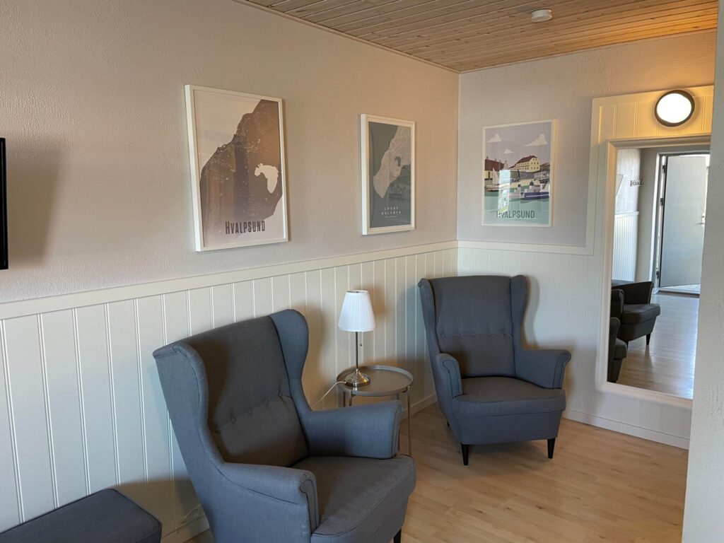 Hyggelig stue med to grå lænestole og kunst